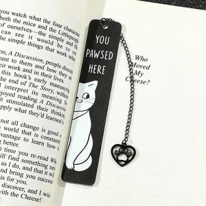 Cute black metal cat bookmarks on book page with heart-shaped chain accessory.