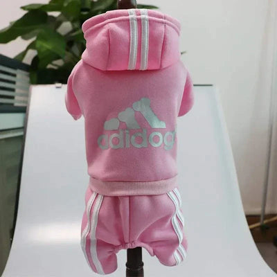 Small dog in pink Adidog fleece hoodie jumpsuit, featuring fashion-forward design for autumn/winter.