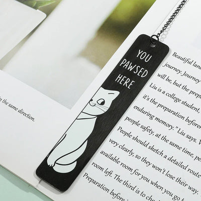 Cute black metal cat bookmarks on open book page, featuring a playful cat design with "You Pawsed Here" text.