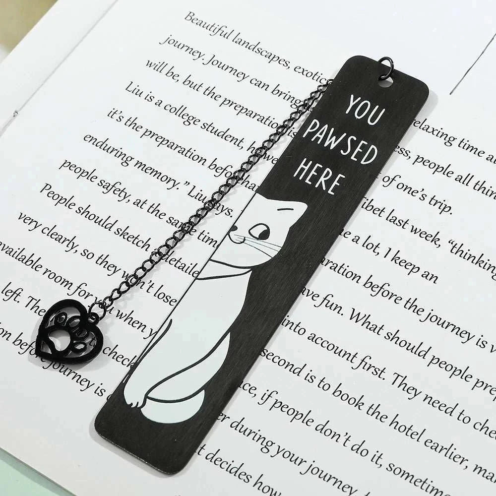 Cute black metal cat bookmarks on open book, perfect for book lovers.